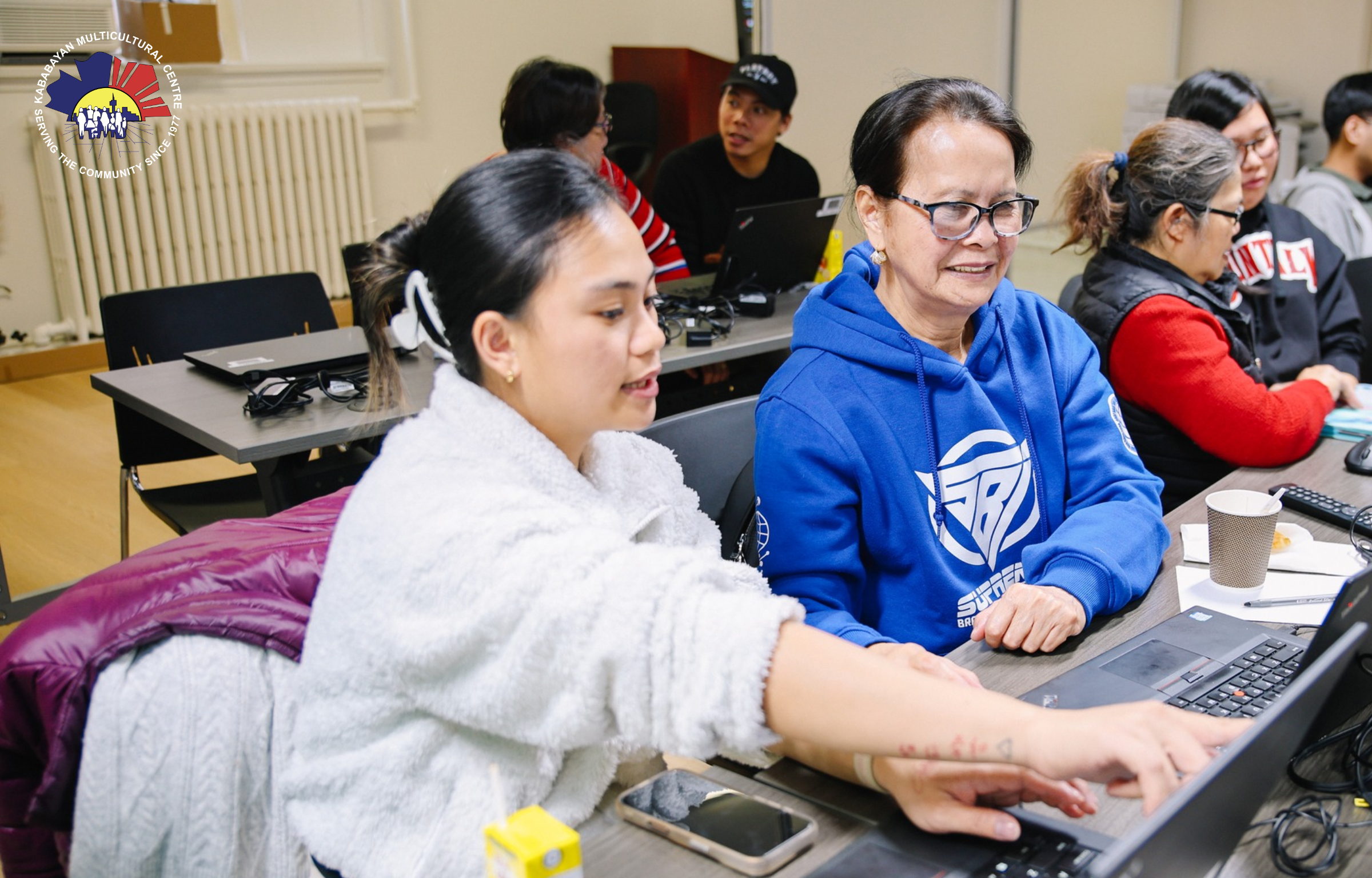 A senior working with a volunteer at a Computer Training workshops for seniors.